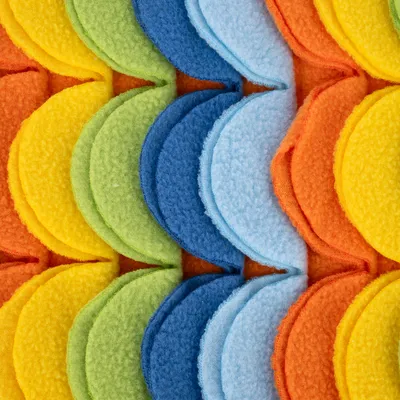 Zbliżenie kolorowych warstw filcu w kształcie półkola, kolory: żółty, zielony, niebieski, pomarańczowy. Widoczna struktura materiału.