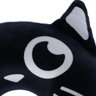 Fekete plüss párna macska formában, fehér szemekkel és fülekkel, dekorációként vagy ölelős párnaként használható.