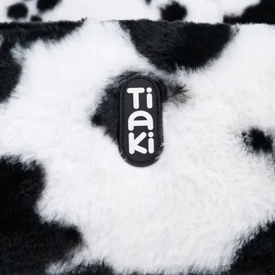 Tiaki logo on black and white faux fur with cow pattern.