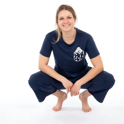 Tricou albastru închis cu motiv de câine pe buzunarul de la piept, combinat cu pantaloni albastru închis. Îmbrăcăminte de agrement pentru iubitorii de animale de companie.