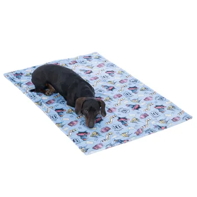 Cane sdraiato su una coperta blu con motivo colorato di simboli come auto, numeri e francobolli.