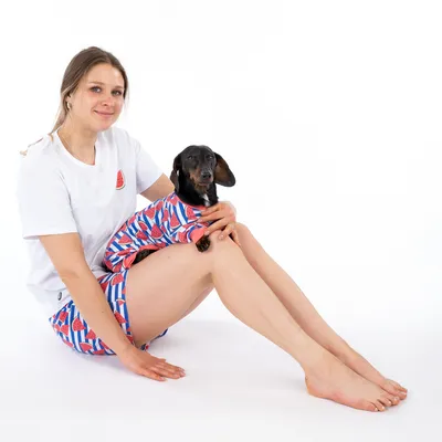 Hund in einem bunten Outfit mit Wassermelonenmuster, passend zum ähnlichen Outfit der Person daneben.