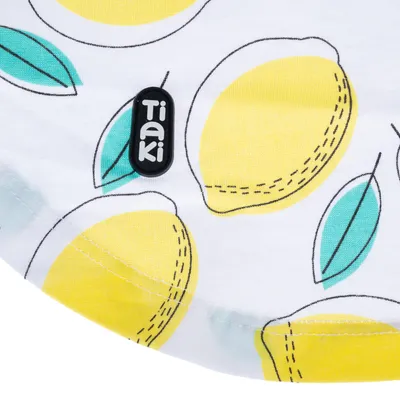 Tissu blanc avec motifs citrons jaunes et feuilles vertes, étiquette visible avec le nom de la marque Tiaki.