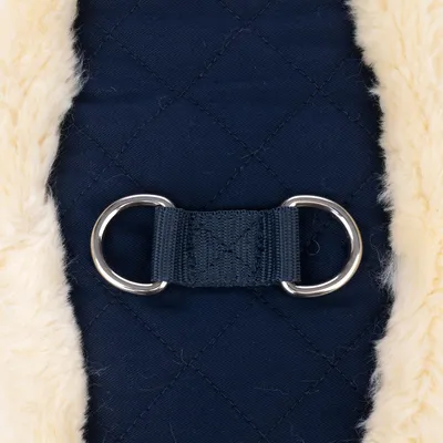 Close-up van donkerblauwe, gewatteerde stof met twee zilverkleurige metalen ringen en crèmekleurige kunstbont rand.