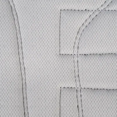 Gros plan sur un tissu matelassé gris clair avec coutures visibles, matière textile à petits motifs réguliers.