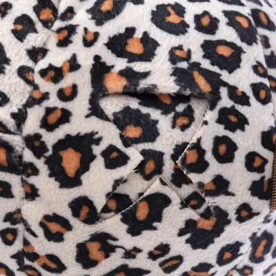 Nærbillede af stofmateriale med leopardmønster i sort, brun og hvid. Synlig søm med overlappende stoflag.