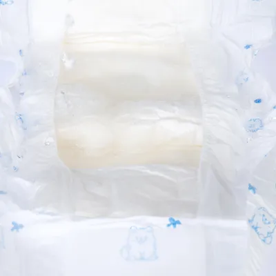 Close-up van een absorberende laag met blauwe hondmotieven op een witte ondergrond, geschikt voor hygiëneproducten.
