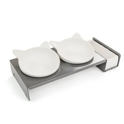 Podwójna miska ceramiczna w kształcie kociej głowy na podwyższonym metalowym stojaku, odpowiednia na karmę lub wodę.