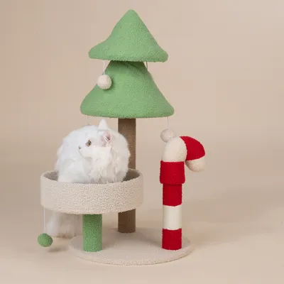 Drapak w świątecznym wzorze z zielonym drzewkiem, czerwonym elementem w kształcie laski cukrowej i beżową platformą. Biały kot siedzi na platformie.