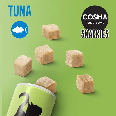 COSMA PURE LOVE SNACKIES, TUNA. Flera kubformade bitar och en grön förpackning med siluett av katt synliga.