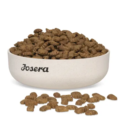 Bol cu crochete maro, pe care este inscripționat numele mărcii Josera. Câteva crochete sunt așezate în fața bolului. Bol cu crochete maro, pe care este inscripționat numele mărcii Josera. Câteva crochete sunt așezate în fața bolului.