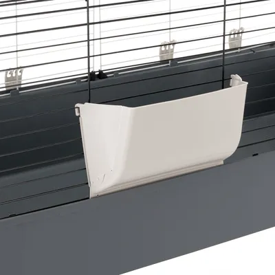 Weißer Futternapf aus Kunststoff, befestigt an einem grauen Käfig mit Metallgitter.