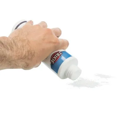 Mano che versa polvere bianca da un flacone con etichetta blu e scritta visibile 'TRIXIE'.
