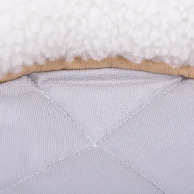 Detail šedé textilní podložky s bílým plyšovým okrajem a béžovým lemem, viditelné prošívání materiálu.