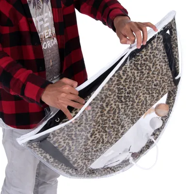 Persona muestra una bolsa de transporte transparente con estampado de leopardo y juguetes en su interior, adecuada para guardar accesorios para mascotas.