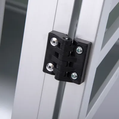 Zawias z czarnego plastiku zamocowany na aluminiowej ramie, widoczne cztery śruby montażowe. Element konstrukcyjny klatki lub transportera dla zwierząt.