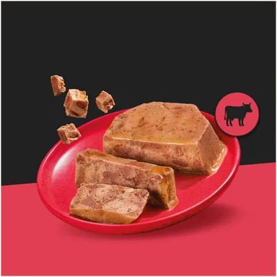 Chunky wet food in cubes and slices on a red plate, next to it a symbol with a silhouette of a cow. Chunky wet food in cubes and slices on a red plate, next to it a symbol with a silhouette of a cow.