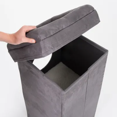 Siva kocka s uklonjivim podstavljenim poklopcem, otvorom sa strane i mekanom unutrašnjom površinom. Ruka podiže poklopac.