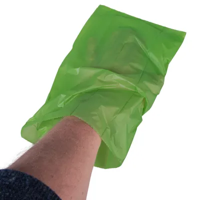 Grüne Hundekotbeutel, über die Hand gezogen, zur hygienischen Entsorgung von Tierabfällen.