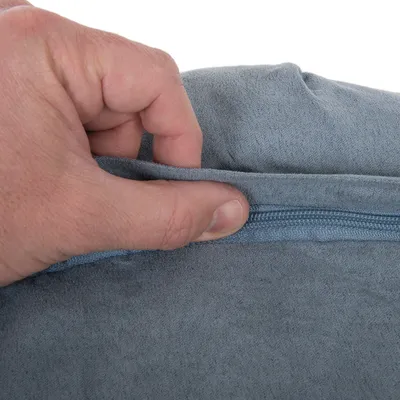 Hånd åbner en skjult lynlås i gråt stofbetræk, viser detalje af betrækkets lukning og materiale.