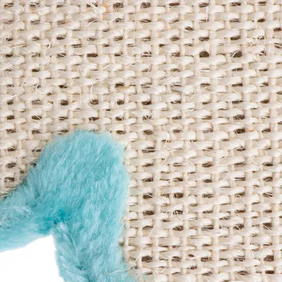 Gros plan sur une surface en sisal tressé avec un détail de tissu bleu pelucheux visible dans le coin inférieur gauche.