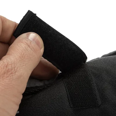 Detailní záběr na černý suchý zip otevíraný rukou. Ukazuje funkci uzavíracího mechanismu.