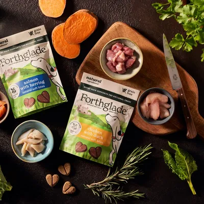 Forthglade natural soft bites in salmon with herring and chicken with duck flavours, shown with heart-shaped treats and fresh ingredients including sweet potato and herbs.