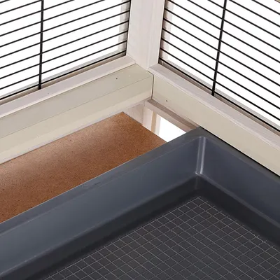 Close-up view of an enclosure with wooden frame, black mesh walls and a removable plastic tray with non-slip surface.