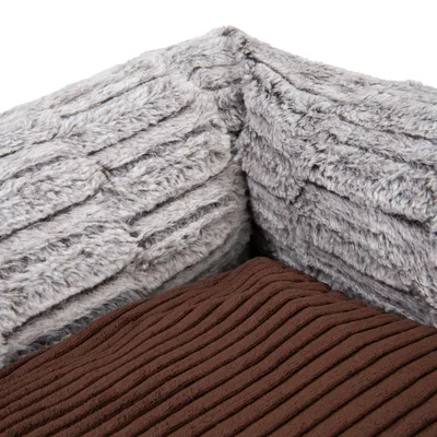 Detailaufnahme eines braunen, gerippten Stoffkissens und einer grauen, plüschigen Wandstruktur. Materialkombination für Haustierbett sichtbar.