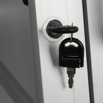 Detailní záběr na černý klíč s gravurou '675', zasunutý v zámku na stříbrném kovovém povrchu.
