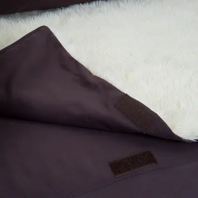 Nahaufnahme einer braunen Decke mit Klettverschluss und weisser, flauschiger Innenseite.