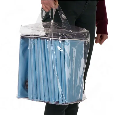 Oseba drži prozorno plastično torbo z ročaji, v kateri so zložene modre podloge. Izdelek je namenjen prenašanju ali shranjevanju podlog.