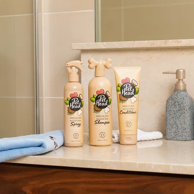 Pet Head Sensitive Soul spray per pelle delicata 300 ml, shampoo 475 ml e balsamo 250 ml al profumo di cocco su mensola del bagno.