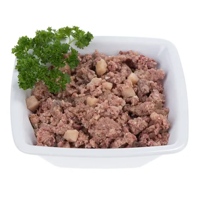 Ciotola con cibo umido composto da pezzi di carne e guarnito con prezzemolo fresco.