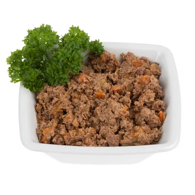 Schüssel mit feuchtem Tierfutter, braune Fleischstücke und orangefarbene Gemüsestücke, dekoriert mit frischer Petersilie.