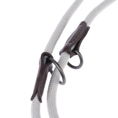 Close-up of a grey rope lead with brown leather accents and black metal rings.