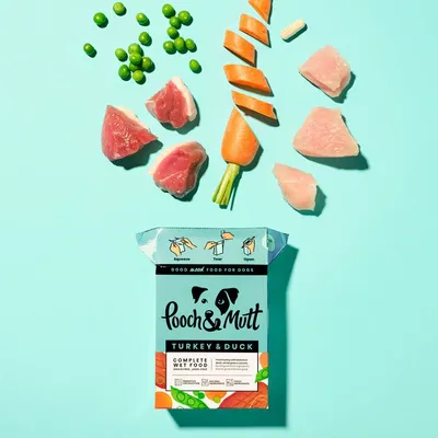 Image shows peas, carrot pieces, raw meat chunks and a carton labelled 'Turkey & Duck Complete Wet Food' with illustrated instructions: squeeze, tear, open.