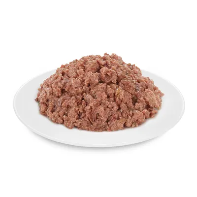 Apróra vágott, barna színű nedves állateledel fehér tányéron, mártásban tálalva. Csomagolás vagy márkanév nem látható.