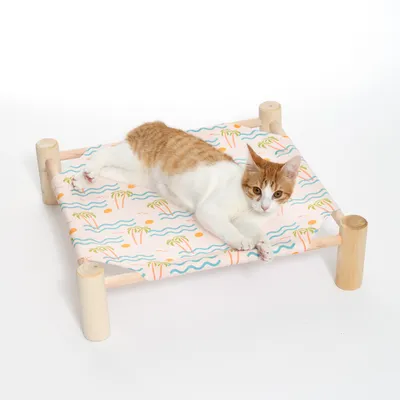 Katzenliege mit Holzrahmen und Stoffbezug im tropischen Design, orange-weisse Katze liegt darauf.