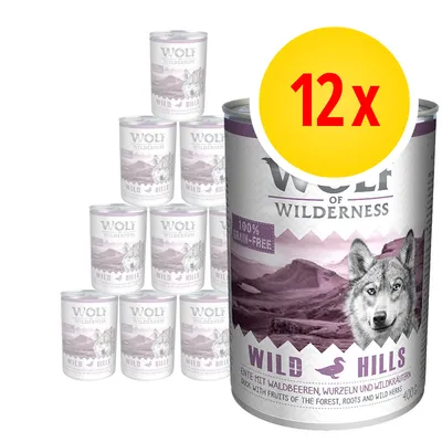 Wolf of Wilderness Wild Hills koiran märkäruoka, 12 x 400 g säilykepakkaus. Etiketissä teksti: 100 % grain-free, Wild Hills, ankka, metsämarjat, juuret ja villiyrtit.