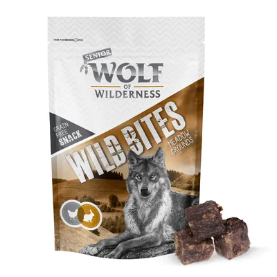 Wolf of Wilderness Senior Wild Bites Meadow Grounds, spannmålsfri snack. Bild på varg och tre bitar av produkten synliga framför förpackningen.