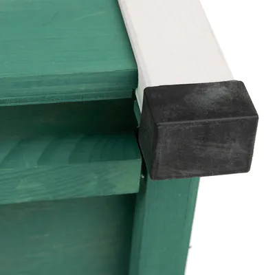 Dettaglio di una struttura in legno verde con bordo bianco e protezione in plastica nera sull’angolo.