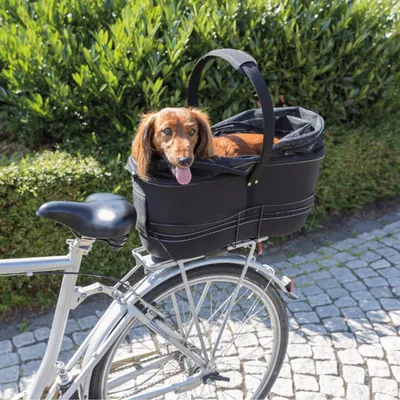 Kosz rowerowy w kolorze czarnym z uchwytem, zamontowany na bagażniku rowerowym. Odpowiedni do transportu zwierząt domowych.
