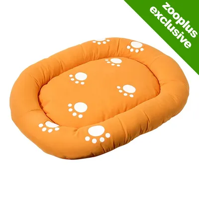 Orange oval pet bed with white paw print designs, shown on a plain background. Green corner banner reads 'zooplus exclusive'.