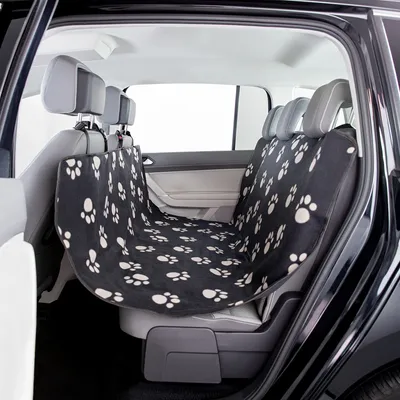 Housse noire à motifs pattes blanches installée sur la banquette arrière d’une voiture, couvrant l’assise et le dossier, fixée aux appuie-têtes. Matière textile visible.