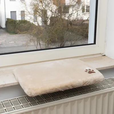 Beige windowsill pad with soft surface and brown paw motif, placed on a windowsill above a radiator.