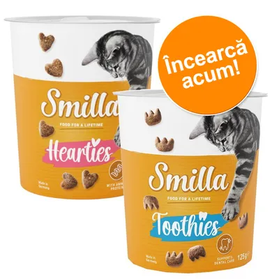 Două recipiente Smilla pentru pisici: Hearties și Toothies, 125 g, cu imagine de pisică și text promoțional portocaliu „Încearcă acum!” pe ambalaj.
