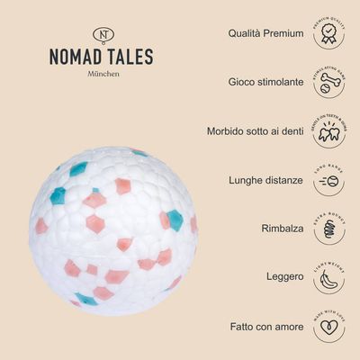 Nomad Tales München, pallina bianca con dettagli rosa e azzurri. Testo: Qualità Premium, Gioco stimolante, Morbido sotto ai denti, Lunghe distanze, Rimbalza, Leggero, Fatto con amore.