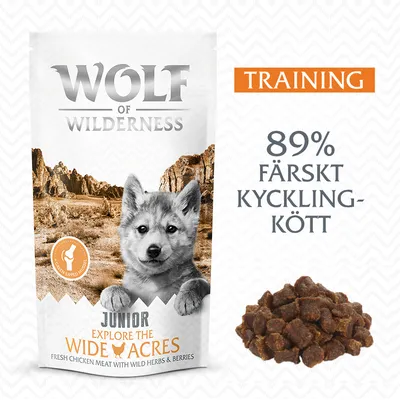 Wolf of Wilderness Junior Explore the Wide Acres hundgodis, text: TRAINING, 89 % färskt kycklingkött. Bild på förpackning och bitar av godiset. Wolf of Wilderness Junior Explore the Wide Acres hundgodis, text: TRAINING, 89 % färskt kycklingkött. Bild på förpackning och bitar av godiset.