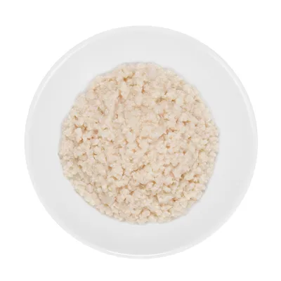 Close-up of white, shredded wet food in a white bowl.